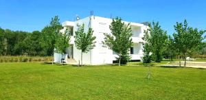 a white house with a green lawn in front of it at Riviera Inn apartments in Ulcinj