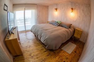 a small bedroom with a large bed and a window at Casa Alma - Lujo y descanso con vista al mar in Pichilemu