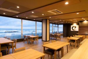 um restaurante com mesas e cadeiras e vista para o oceano em Ikkyu -Seaside Hotel- em Tsuruoka