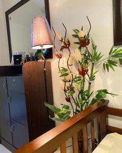 eine Blumenvase in einem Zimmer mit einer Lampe in der Unterkunft Cozy Boo Bed and Breakfast near Enchanted Kingdom by Dynel in Santa Rosa