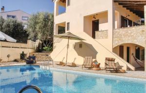 a swimming pool with chairs and an umbrella next to a house at Awesome Home In Aigio With 3 Bedrooms, Wifi And Outdoor Swimming Pool in Aigio