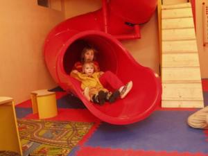 zwei Kinder sitzen in einem roten Spielhaus in der Unterkunft Gasthof Zur Post in Bad Goisern