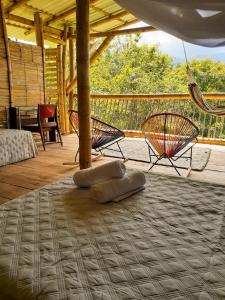 een kamer met een hangmat en stoelen op een veranda bij El Cielo Biohospedaje in Tena