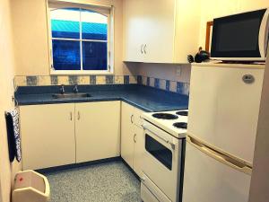 a kitchen with a white refrigerator and a sink at ASURE Surrey Court Motel Invercargill in Invercargill
