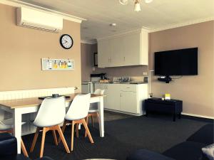 a living room with a table and chairs and a kitchen at ASURE Surrey Court Motel Invercargill in Invercargill