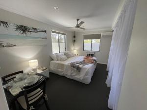 a bedroom with a bed and a table and two windows at Torquay Terrace Bed & Breakfast in Hervey Bay