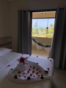 a bed with a cake with roses on it with a window at Pousada Costa dos Corais in São José da Coroa Grande