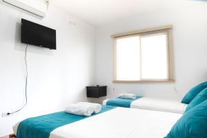 a bedroom with two beds and a flat screen tv at Ocean Blue Hotel in Olón