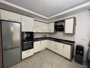 a kitchen with white cabinets and a stainless steel refrigerator at Stylish Ground floor 3-Bed Apartment in Dalyan in Ortaca