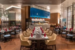 InterContinental Dhaka, an IHG Hotel في داكا: غرفة طعام مع طاولات وكراسي في مطعم