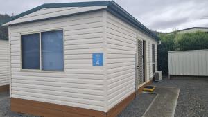 a small white shed with a blue sign on it at Discovery Parks - Mornington Hobart in Hobart