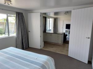 a white bedroom with a bed and a mirror at Bethlehem Apartment in Tauranga