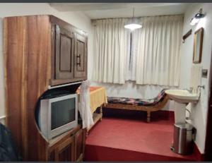 a room with a bed and a television and a sink at Coffee Inn in Thekkady