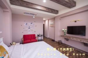 a bedroom with a red chair and a tv at Deer Gaomei in Qingshui