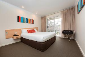 a hotel room with a bed and a window at Ramada Encore Belconnen in Canberra