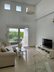 ein Wohnzimmer mit einem Sofa und einem TV in der Unterkunft Fantastica villa con piscina en gran golf resort in Roldán