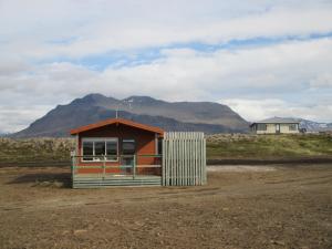 Langafjaran Cottages في Hjarðarfell: منزل صغير في حقل مع جبل في الخلفية
