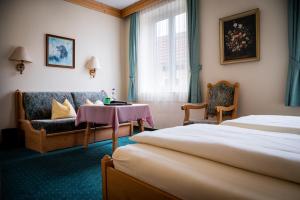 ein Hotelzimmer mit einem Bett, einer Couch und einem Tisch in der Unterkunft Hotel Krug in Gumpoldskirchen