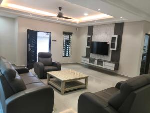 a living room with couches and a flat screen tv at Orkid Apartment in Cameron Highlands