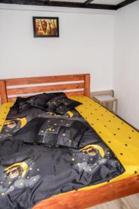 a bed with a black and yellow comforter at Cabana „Stâna din Deal” in Proviţa de Sus