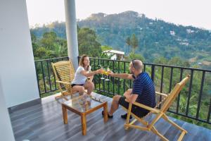 a man and woman sitting on a balcony drinking wine at Cozy Resort Ella in Ella