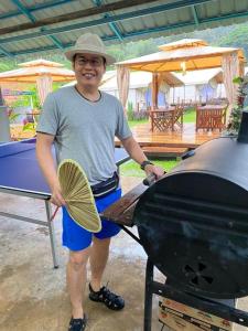 a man standing next to a grill with a fan at Canopy Villa Tampik Valley in Kampong Sum Sum