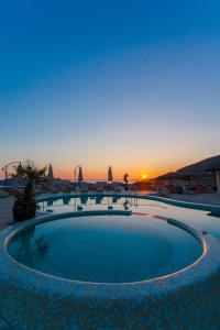 a large swimming pool with a sunset in the background at Spa Resort Luxury Apartments in Budva