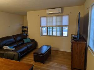 a living room with a leather couch and a flat screen tv at Warm and Welcoming 2BR close to UNM North Campus in Albuquerque