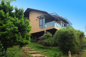 a house with a balcony on a hill with trees at Tea Terrain Resorts & Spa in Vagamon