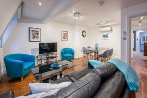 a living room with a leather couch and blue chairs at Apartment 4, 48 Bishopsgate by City Living London in London