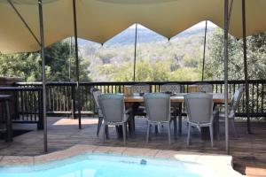 uma mesa e cadeiras num deque ao lado de uma piscina em Khululeka Guest Farm em Millvale