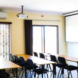 a classroom with tables and chairs and a projection screen at Estoby Executive guest house in Witbank