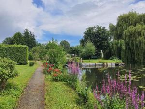 einen Garten mit einem Teich und Blumen in der Unterkunft Le Cottage des Hortillonnages in Amiens