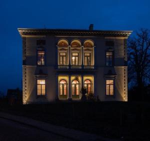una casa grande con sus luces encendidas por la noche en Villa Servais en Halle