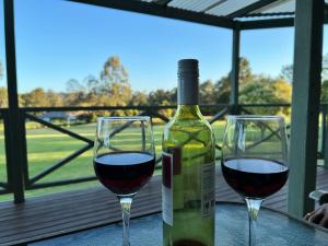 a bottle of wine and two glasses on a table at Carinya Cottage Hunter Valley - Nature retreat in Aberdare