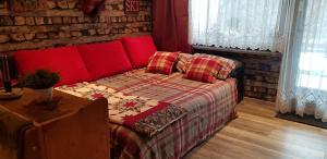 a bedroom with a red couch and a brick wall at Maisalm, Apt 4 in Maishofen