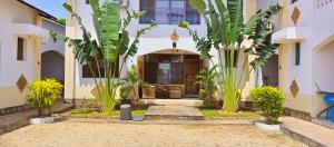 a house with palm trees in front of it at Simba Apartments in Diani Beach