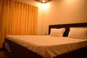 1 dormitorio con 1 cama grande con sábanas y almohadas blancas en Nature Heights BNB en Nainital