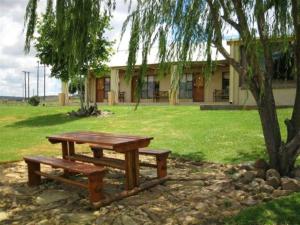 a picnic table and a tree in front of a building at Suites in Private Game Reserve close to Aliwal North in Gladdegrond