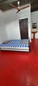 1 dormitorio con 1 cama y suelo rojo en Moray homestay, en Malvan