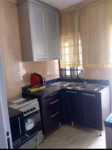 a small kitchen with a stove and a sink at XrisBun Apt 1BR - Laderin GRA in Abeokuta