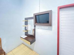 ein Wohnzimmer mit einem TV an der Wand in der Unterkunft Homestay Tirtasari Pinrang City Center Mitra RedDoorz in Pinrang