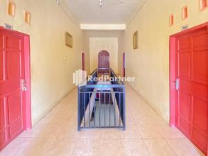 una stanza con due porte rosse e un corridoio di Homestay Tirtasari Pinrang City Center Mitra RedDoorz a Pinrang