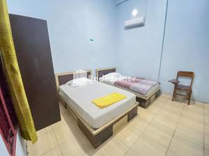 1 Schlafzimmer mit 2 Betten und einem Stuhl in der Unterkunft Homestay Tirtasari Pinrang City Center Mitra RedDoorz in Pinrang + 18 Fotos
