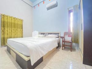 ein Schlafzimmer mit einem Bett und einem Stuhl darin in der Unterkunft Homestay Tirtasari Pinrang City Center Mitra RedDoorz in Pinrang