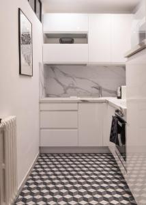 a kitchen with white cabinets and a black and white tile floor at Magnolia : Superbe deux-pièces quartier du Château in Pau