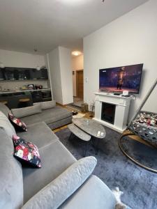 a living room with a couch and a tv at Bjelasnica White apartmani in Bjelašnica