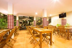 a restaurant with wooden tables and wooden chairs at Manggar Indonesia Hotel in Kuta