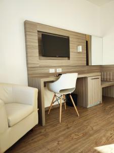 a living room with a desk with a tv and a white chair at Hotel Cristallo in Conegliano +23 photos