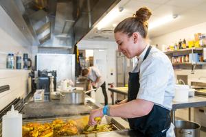 Apex2100 International Ski Academy Tignes في تينيِ: a woman preparing food in a kitchen